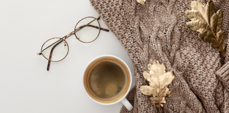 Flat lay of brown glasses with coffee, scarf and gold leaves