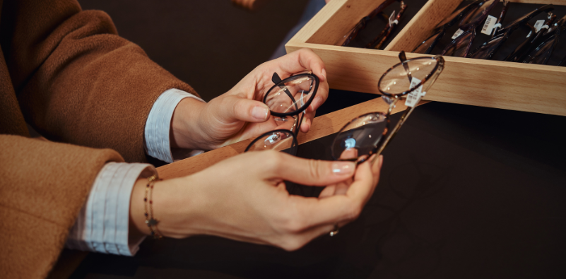A close-up of a woman's hands choosing glasses at the opticians.